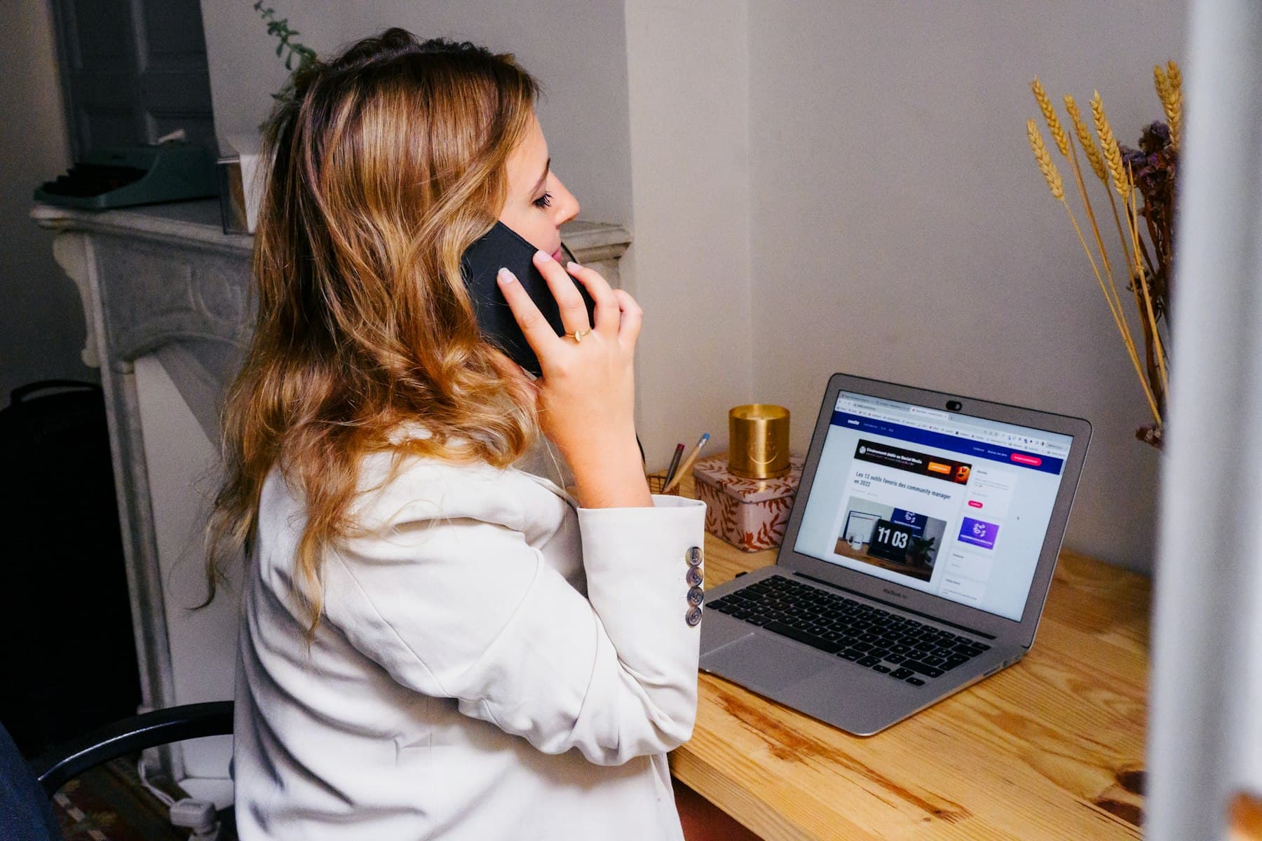 A woman on the phone at her desk with a laptop open